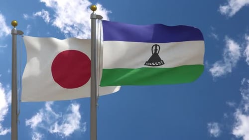 Waving Flags of Japan and Lesotho Against Blue Sky