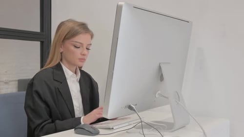 Business Woman Looking at Camera while Working on computer in Office
