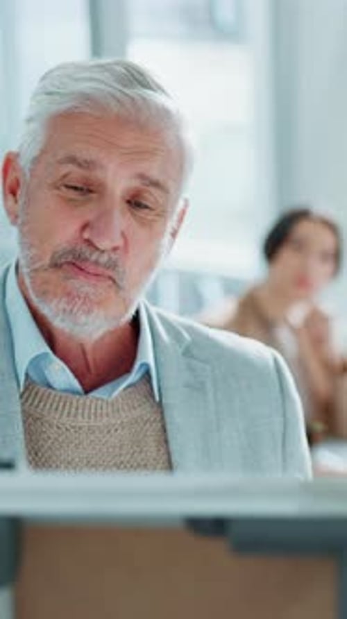 Mature Man Leads Meeting with Colleagues Indoors