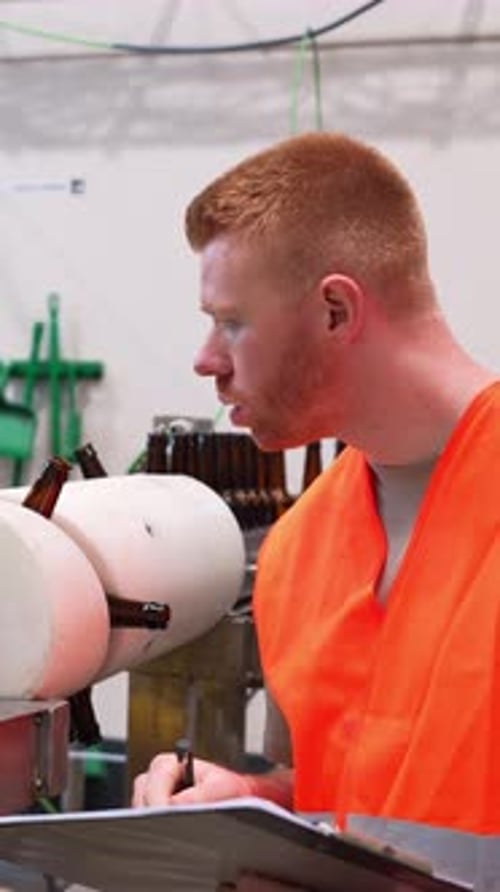 Man Inspecting Bottles on Production Line