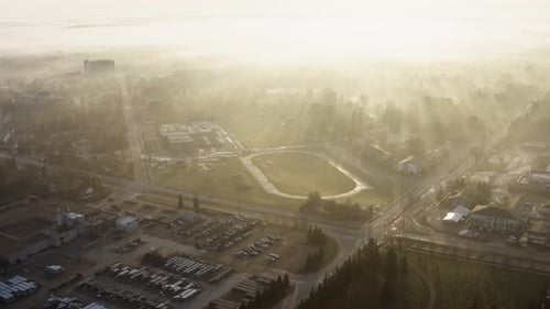 Aerial up over mist foggy morning of sports center in small town Canadian prairie city.