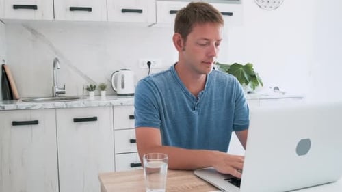 Man Using Laptop in Bright Kitchen Interior