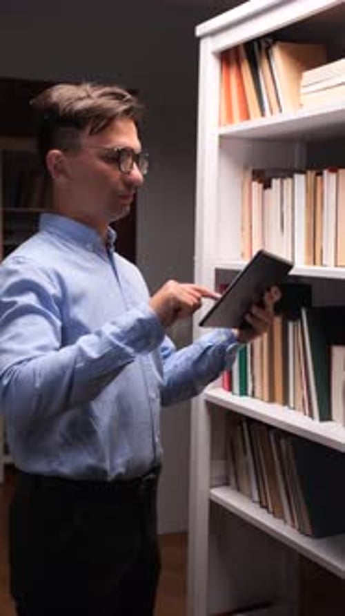 Vertical Video Librarian Using Tablet and Consulting Book Catalog in Library Bookshelf