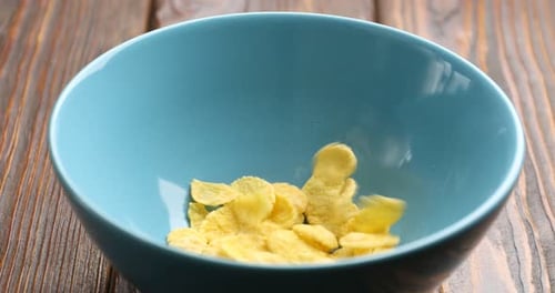 Cereal Flakes Falling into a Light Blue Bowl