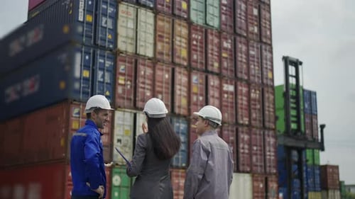 Blue collar workers are working at container warehouse.