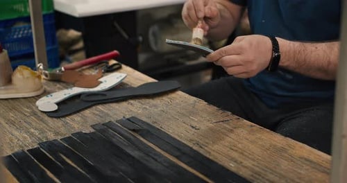 Gloved Adult Applying Glue to Shoe Sole at Workbench