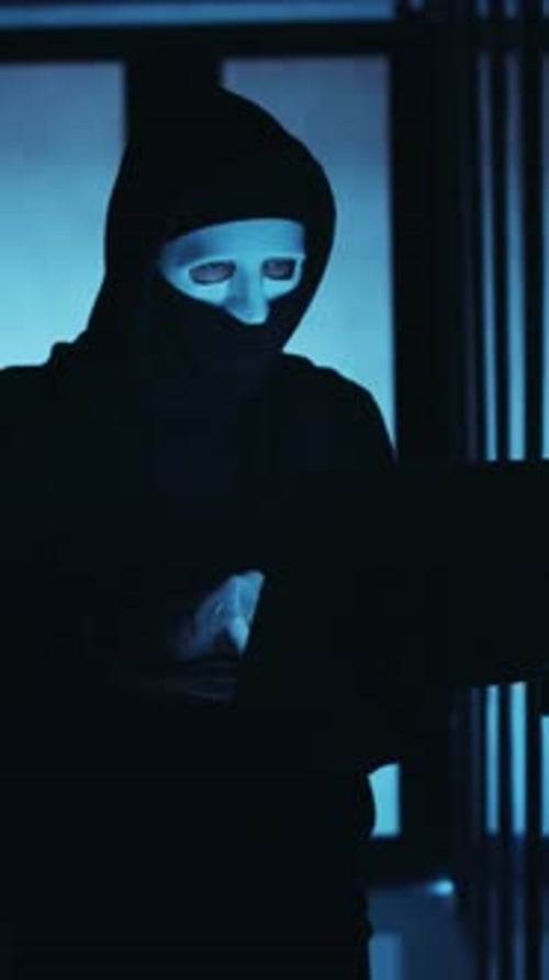 Ein Hacker arbeitet an einem Laptop in einer schwach beleuchteten Umgebung, in der überall fortschrittliche Technologie steckt