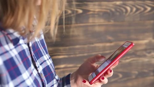 Woman Using Smartphone Against Wooden Wall Close Up