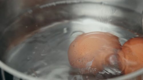 Eier in einem Topf mit Wasser auf einem Herd kochen. Nahaufnahme. 4K