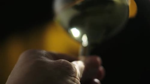 Hand Holding Glass of White Wine at Night