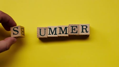 un fond jaune chaud sans ombres, les cubes en bois posés à la main par l'homme avec des mots colorés disposés