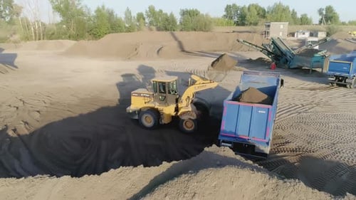 Front Loader Filling Truck with Dirt at Construction Site