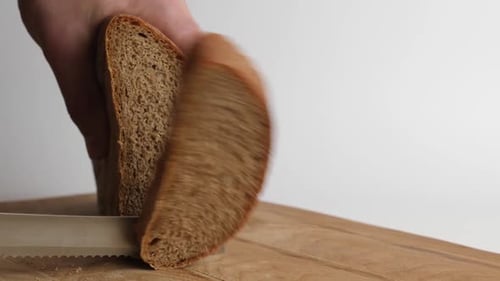 F-120. Brot mit einem Messer auf einem Holzbrett schneiden. Arbeite in der Küche.