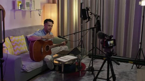 A musician records a guitar tutorial at a home podcast studio.