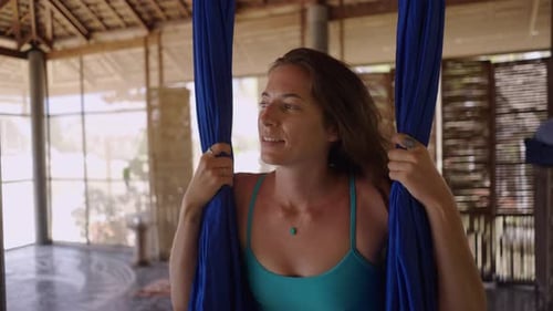 Woman Practices Aerial Yoga in Tropical Studio