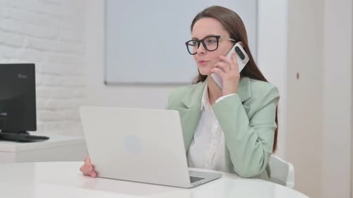 Young Woman Talking on Cell Phone at Desk