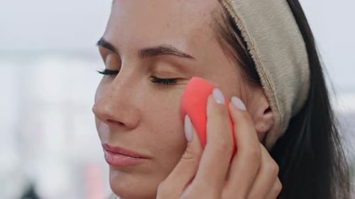 Woman Applying Makeup with a Sponge in Close Up