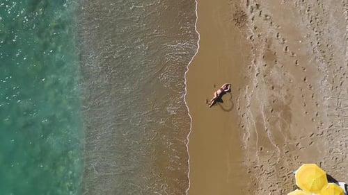 Luftbildmodell, das an einem sonnigen Strand posiert und im azurblauen Wasser schwimmt