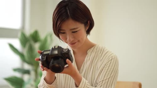 Woman Holding a Digital Camera Indoors