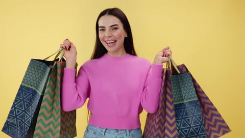 Young Woman Expressing Happiness While Holding Shopping Bags in Studio