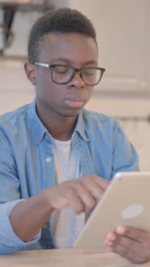 Young Man Uses Tablet Indoors at Table