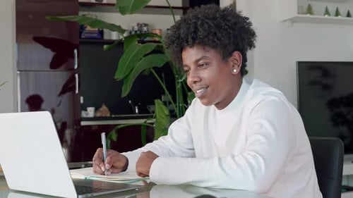 Young Adult Studying with Laptop and Notebook at Home