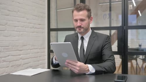 Businessman Celebrating Success with Tablet in Office