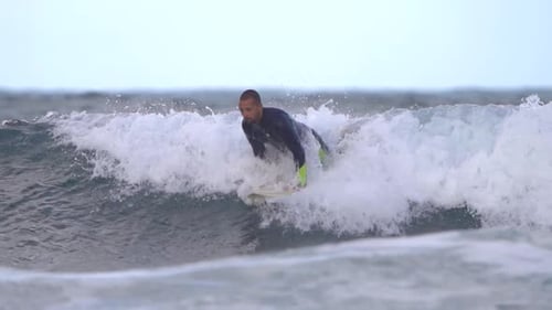 Surfer rides a wave in slow motion at Gran Canaria beach,