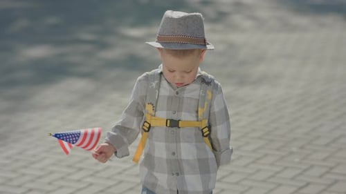 Child Waving American Flag on City Street