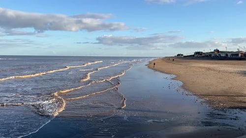 Warm inviting coastal sunset scene with people walking through the image. Warm tones with gentle wav