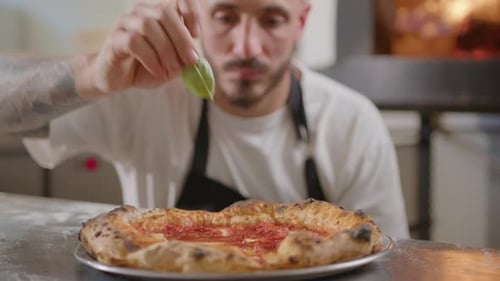 Chef Adding Fresh Basil to Delicious Pizza