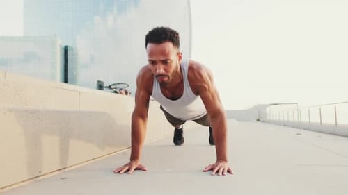 Young athlete doing workout, push ups on the embankment
