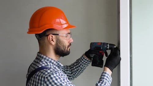 Man in Uniform Does Pvc Window Installation with a Screwdriver
