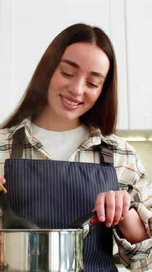Smiling Woman Cooking and Stirring Food in Pot