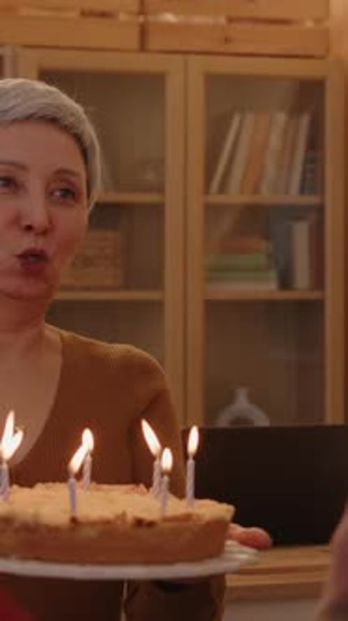 Woman Holding Cake as Candles Blown Out