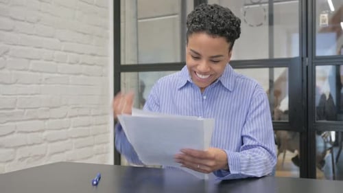 Excited Woman Reading Documents at Office Desk