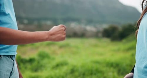 Fist Bump Between Two People Outdoors During Daytime