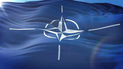 NATO Flag Waving in the Wind with Blue Sky Background