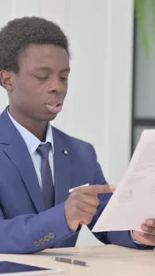 Man in Suit Reading Document with Frustration Indoors