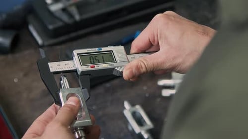 Hands of Anonymous Engineer Scaling Metal Piece with Vernier Caliper