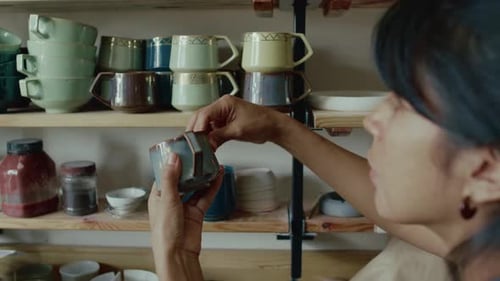 Close-up of Latin Craftswoman Taking Ceramic Cup from Shelf