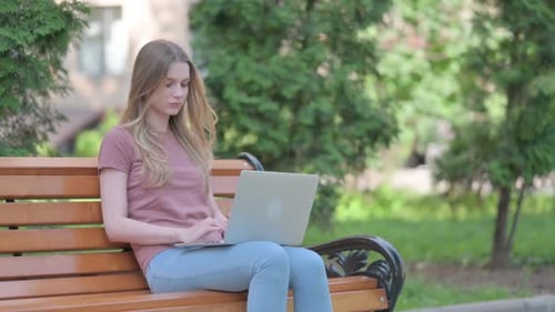 Woman Using Laptop on Park Bench Outdoors
