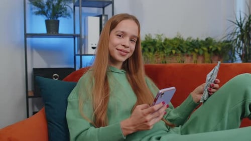 Woman Using Phone with Money on Sofa