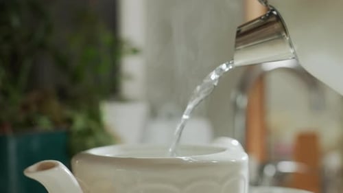 Close Up of Steam Rising As Hot Water Is Poured Into White Mug with Blurred Background