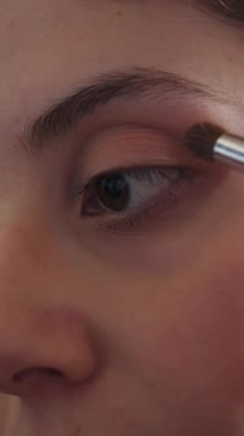Woman Applies Eyeshadow with Makeup Brush Close Up
