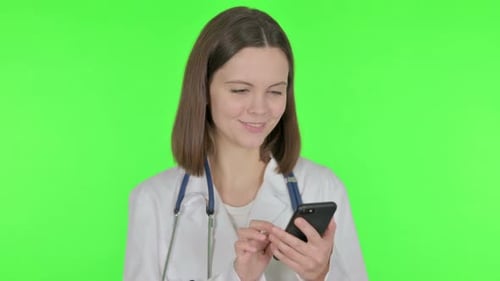 Female Doctor Browsing Smartphone on Green Background