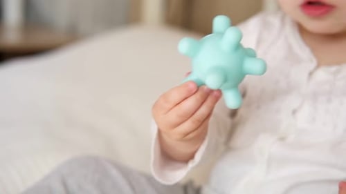 Baby Playing with a Blue Toy Indoors