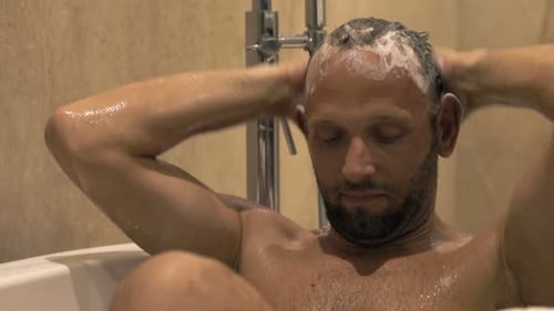 Man washing hair in the tub, smiling