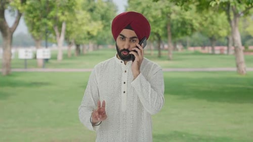 Angry Sikh Indian man shouting on someone on phone in park