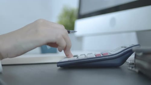 Geschäftsfrau, die mit dem Taschenrechner rechnet und im Büro schreibt